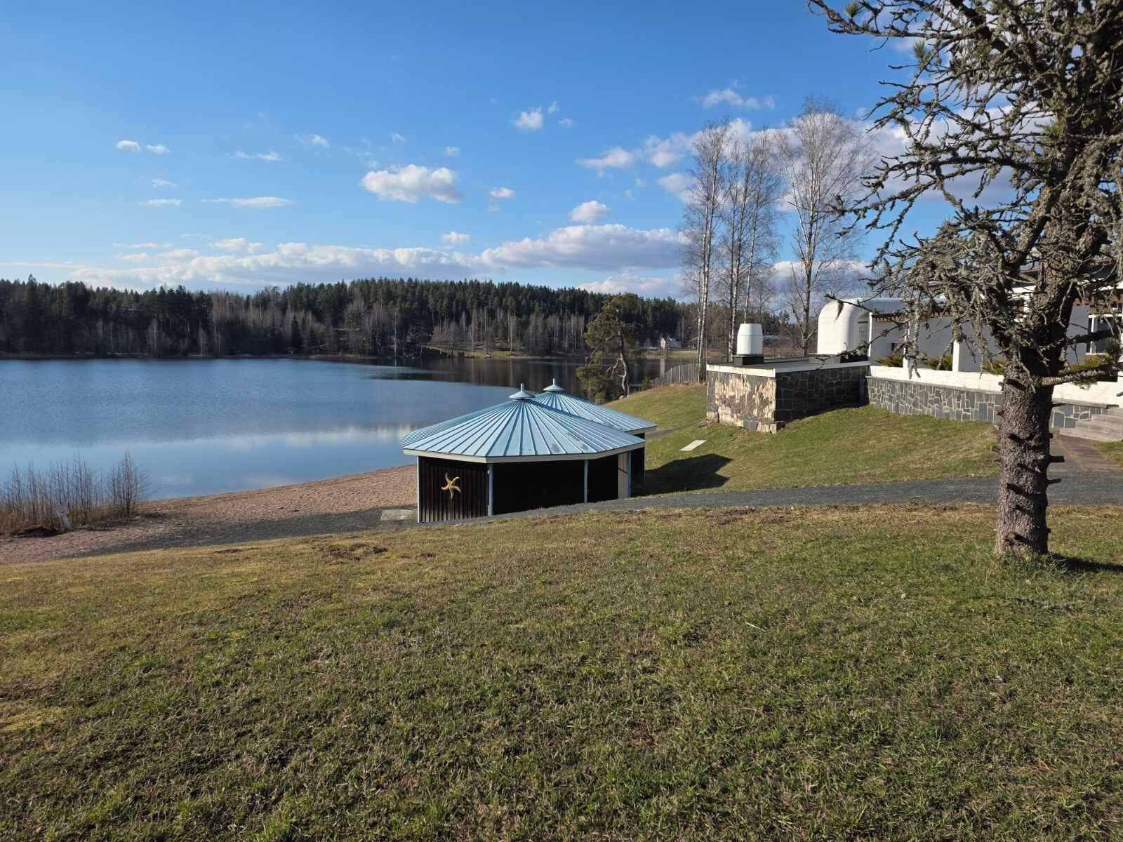 A lakeside property with a gazebo, stone walls, and a view of a lake and forest.