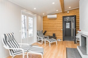 A room with two striped lounge chairs, a small table, and a door leading to another room.