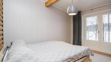 Een slaapkamer met een bed, een raam en een hanglamp.