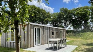 Una cabaña de madera con un patio, una mesa y sillas.