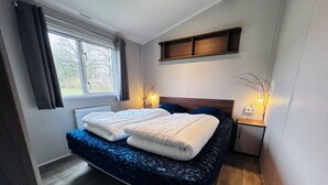 Un dormitorio con cama, mesitas de noche, ventana y estante empotrado.