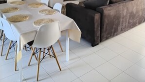 A modern living room with a sofa, dining table, and a flat-screen TV. - Maison avec piscine sur un golf (Fiac)