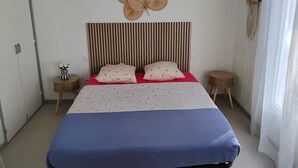 A bedroom with a striped headboard, a large floral wall decoration, two bedside tables, and a bed with a blue and white bedspread. - Maison avec piscine sur un golf (Fiac)