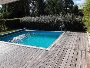 Una piscina rectangular con un deck de madera alrededor.