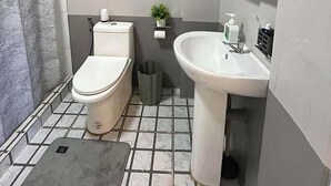 Baño con inodoro, lavamanos y cortina de ducha.