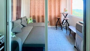 Una habitación con sofá, una mesa y sillas, un calentador y vistas a través de una puerta de cristal.