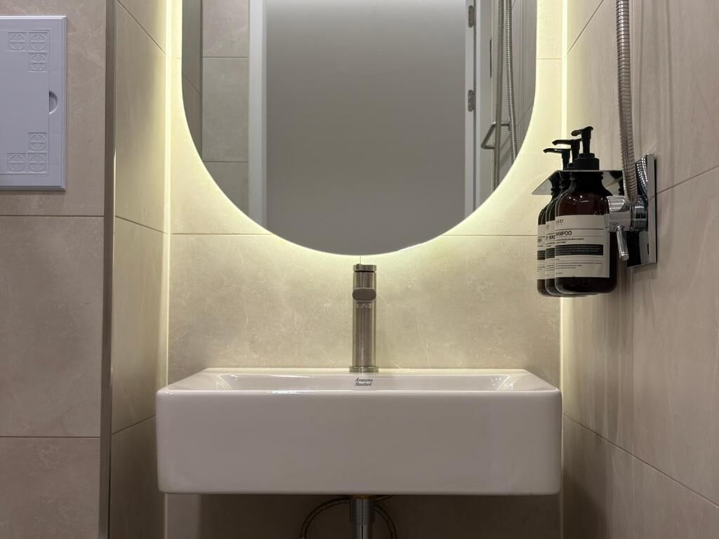 A bathroom with a white sink, a mirror, and a hand soap dispenser.