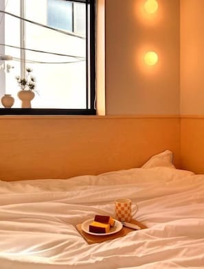 Habitación de hotel con cama, ventana con vistas y lámpara fijada a la pared.