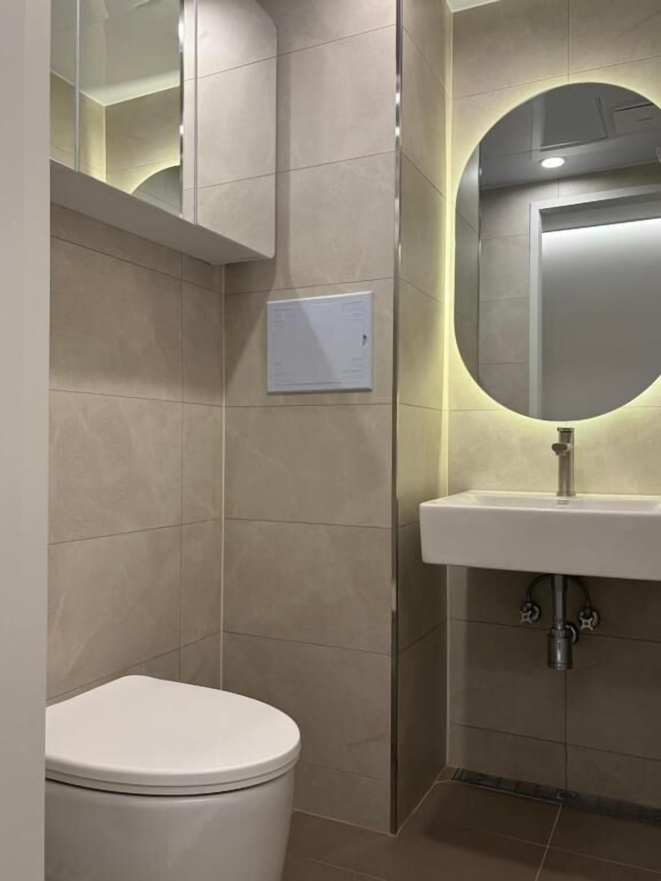 A bathroom with a toilet, a sink, and a mirror.
