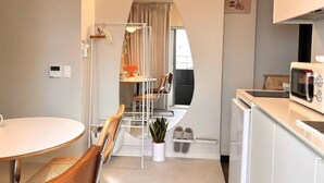 Una cucina compatta con forno a microonde, lavello e zona pranzo con tavolo e sedie.