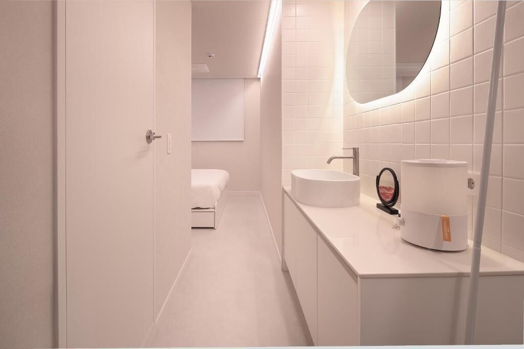 A modern bathroom with a white sink, mirror, and toilet.