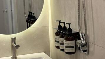 A bathroom with a sink, mirror, and wall-mounted shampoo bottles.