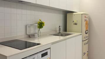 A compact kitchen with a dishwasher, a coffee maker, and a refrigerator.