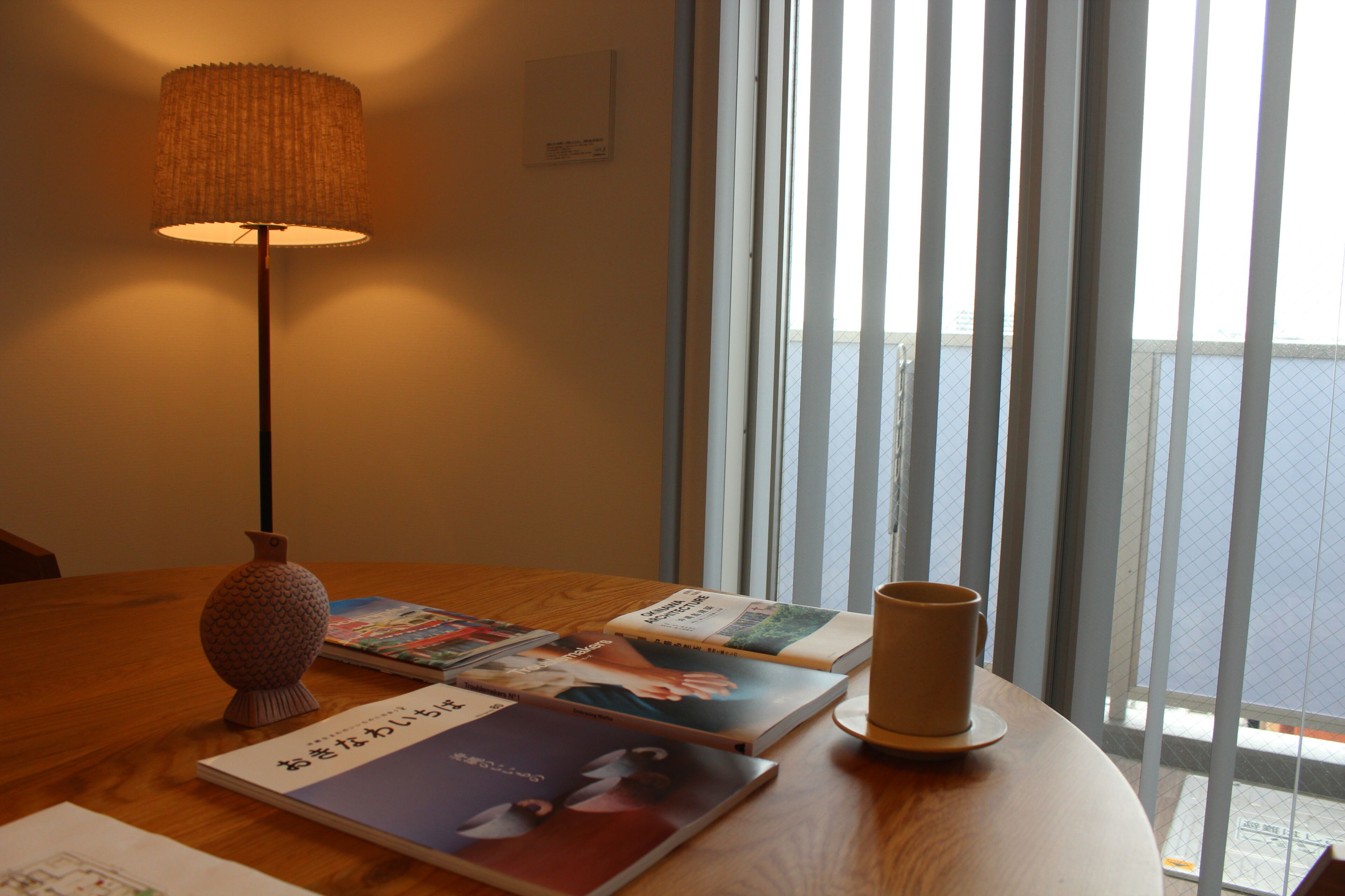 Una habitación con una mesa de madera, una lámpara y libros.