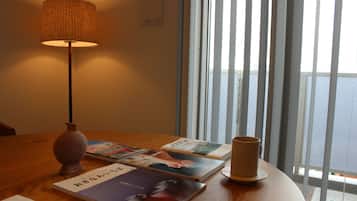 Una habitación con una mesa de madera, una lámpara y libros.