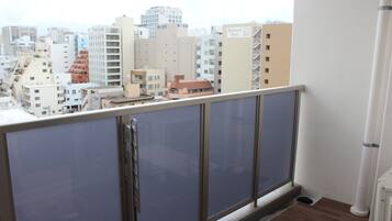 Un balcón con vista a un paisaje urbano, que incluye varios edificios y un cielo despejado.