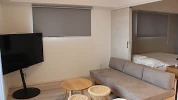 A modern, compact living space with a sofa, a television, and two small tables.