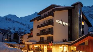 Un hôtel situé dans une région montagneuse, avec une enseigne indiquant « HÔTEL ALPIN ».
