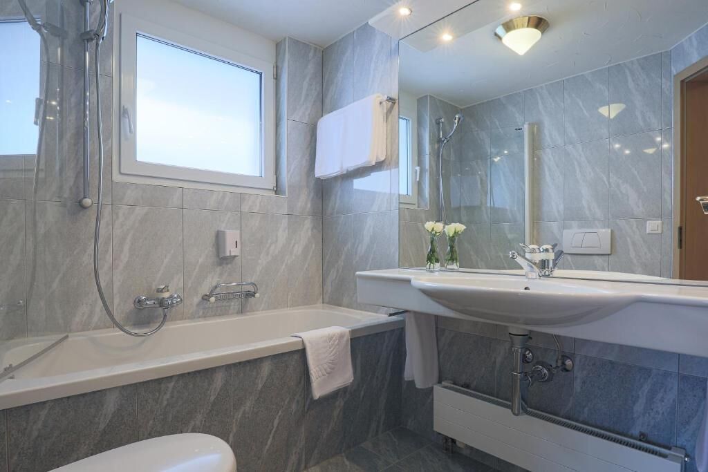 A modern bathroom with a bathtub, a large mirror, and a vanity with a sink.