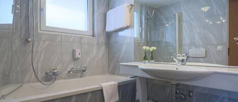 A modern bathroom with a bathtub, a large mirror, and a vanity with a sink.