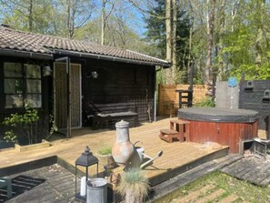 Una cabaña de madera con jacuzzi, mobiliario exterior y una jardinera grande.