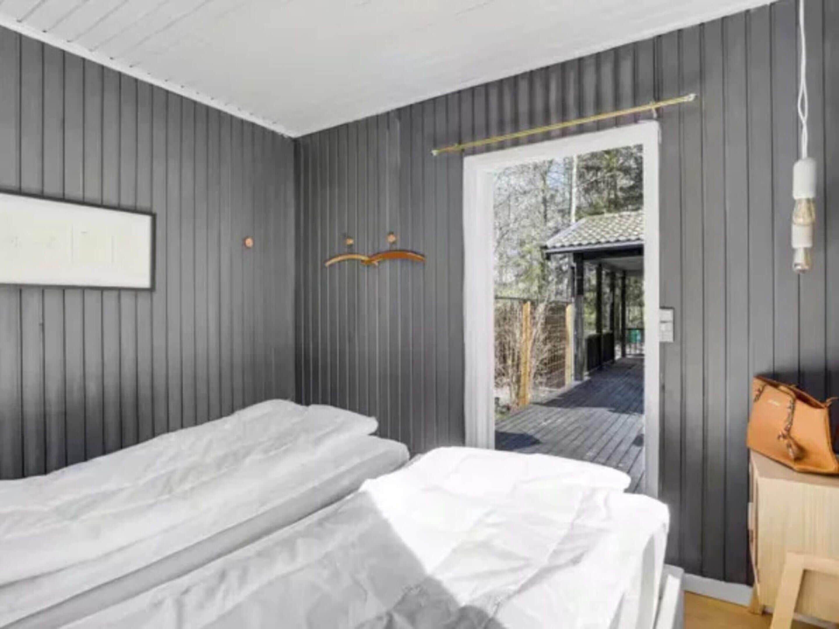 A room with two single beds, a wooden desk, a chair, and a door leading outside.