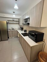 Una cocina moderna con microondas integrado, horno y refrigerador de acero inoxidable.