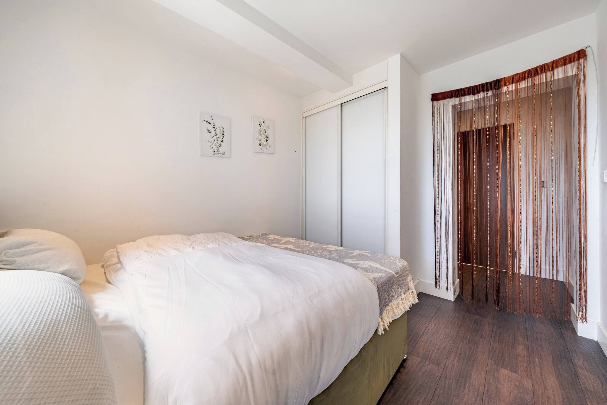 A bedroom with a bed, a wardrobe, and a window with curtains.