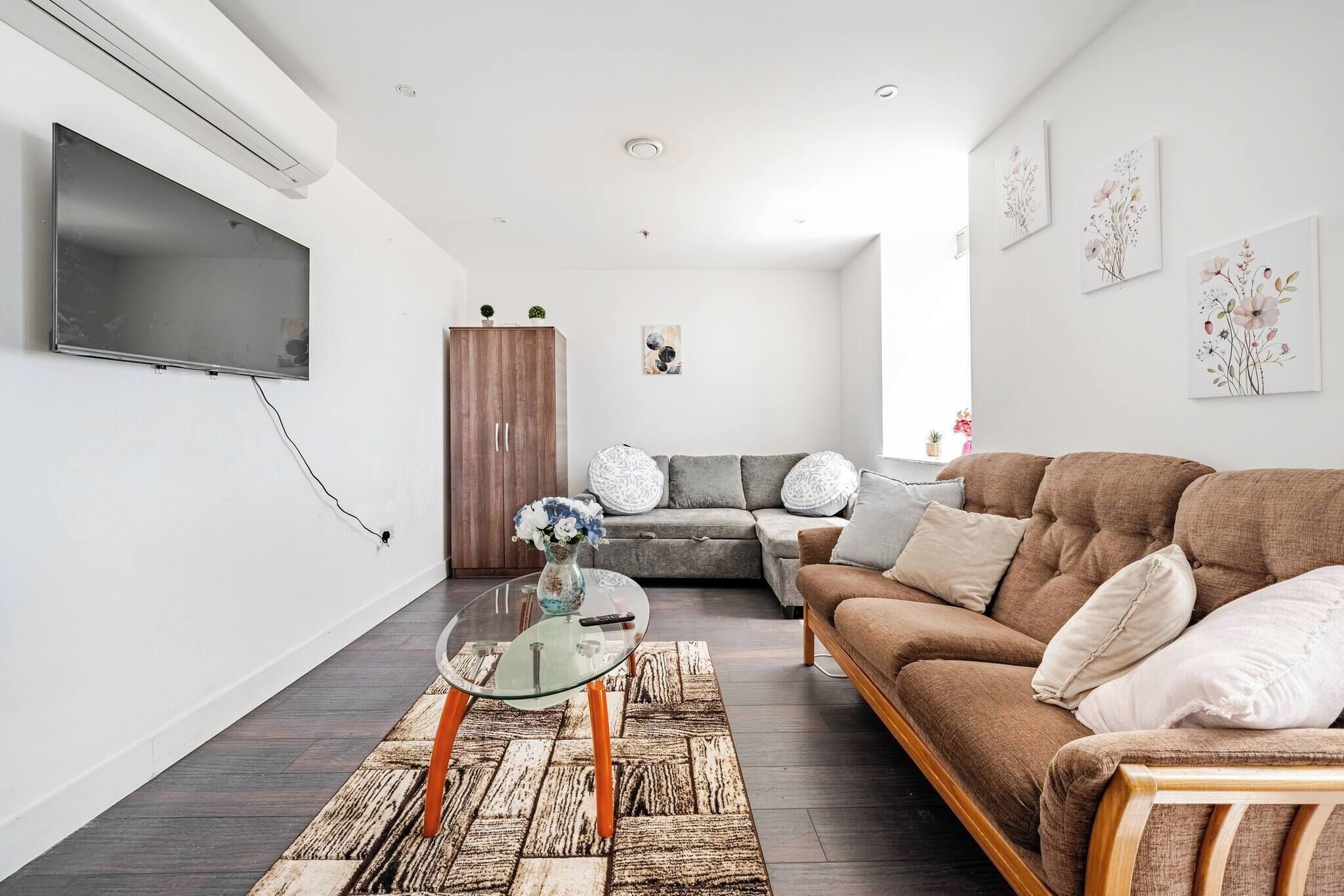 Un salon moderne avec un canapé, une table basse en verre et un téléviseur fixé au mur.