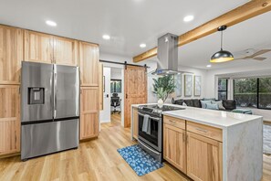 A modern kitchen with wooden cabinets, stainless steel appliances, and a marble countertop. - The Plunge at Red Rock - Cold Plunge, Sauna, Hot Tub, Red Rock Views (Sedona)