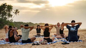 A group of people seated on a beach with a blanket, some with their hands behind their heads, under a cloudy sky. - Rekawa Wellness Resort  (Netolpitiya)