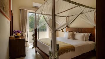 A four-poster bed with a canopy, a wooden headboard, and a bedside table with a vase of flowers.