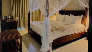 A bedroom with a canopy bed, a bedside table, a chair, and a wooden bench. - Rekawa Wellness Resort  (Netolpitiya)