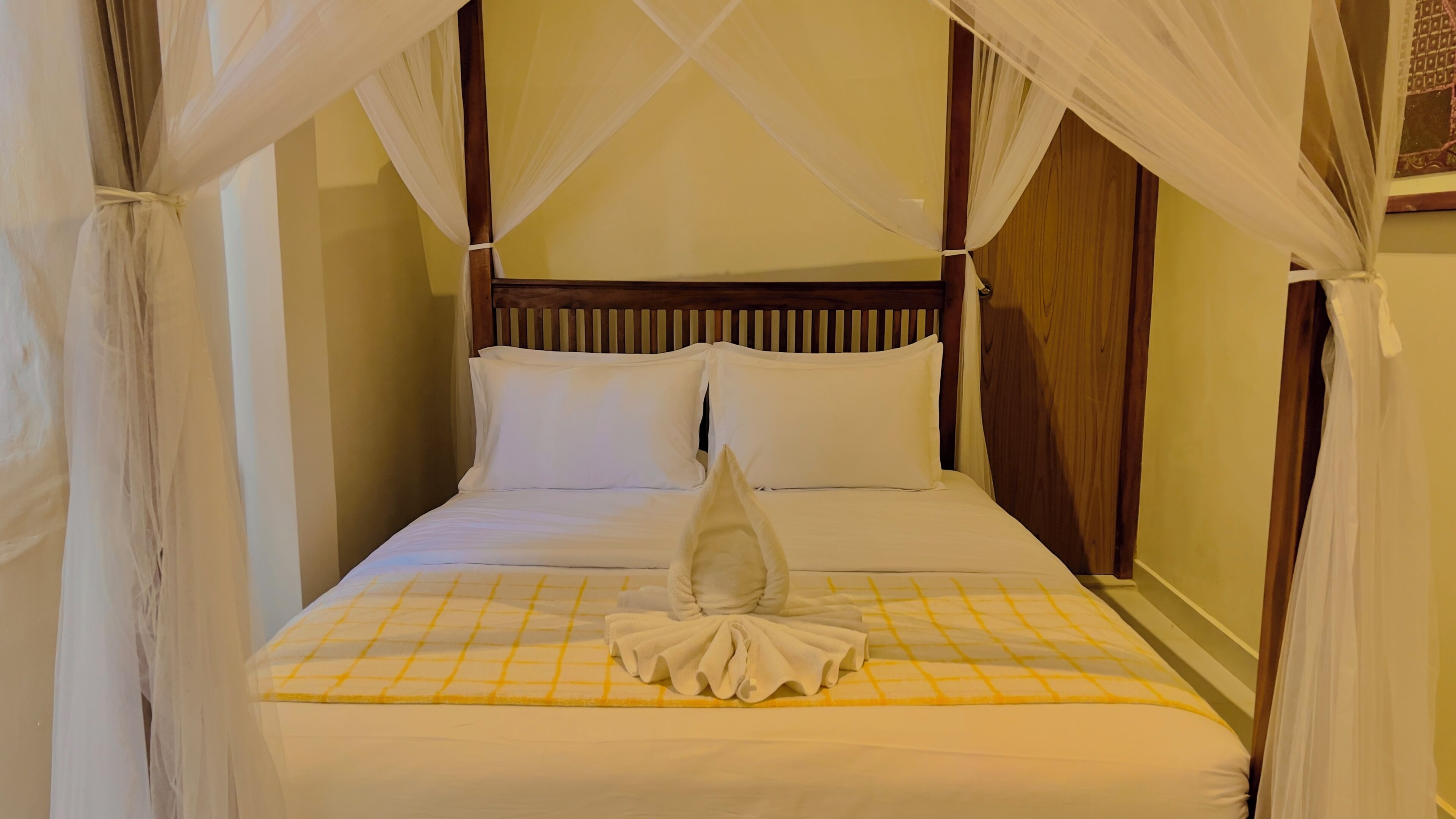 Una cama con dosel, cabecera de madera y colcha a cuadros.