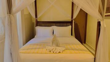 Una cama con dosel, cabecera de madera y colcha a cuadros.