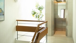 Un interior moderno con una escalera, una planta en maceta y un ascensor.