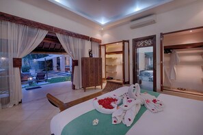 Ein Hotelzimmer mit Bett, einer Holzbank, einem Kleiderschrank und Blick auf einen Garten.