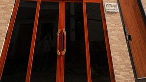 A multi-story building with a prominent entrance featuring large glass doors and a wooden frame. - Zen Living (Ho Chi Minh City)