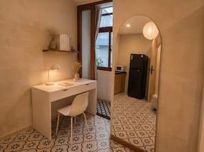 A compact kitchen with a refrigerator, microwave, and a window with curtains. - Zen Living (Ho Chi Minh City)