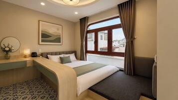 A hotel room with a bed, bedside table, lamp, and a window with curtains.