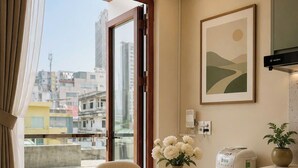 A modern kitchen with a dining area, a view of the city, and a kitchen island with a toaster and a potted plant. - Zen Living (Ho Chi Minh City)