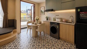 A compact kitchen with a washing machine, a refrigerator, and a dining area with a table and chairs. - Zen Living (Ho Chi Minh City)