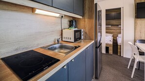 Una cocina compacta con estufa integrada, microondas y refrigerador.