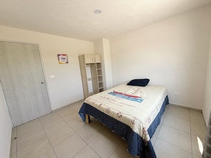 A bedroom with a bed, a wardrobe, a door, and a wall with a poster.