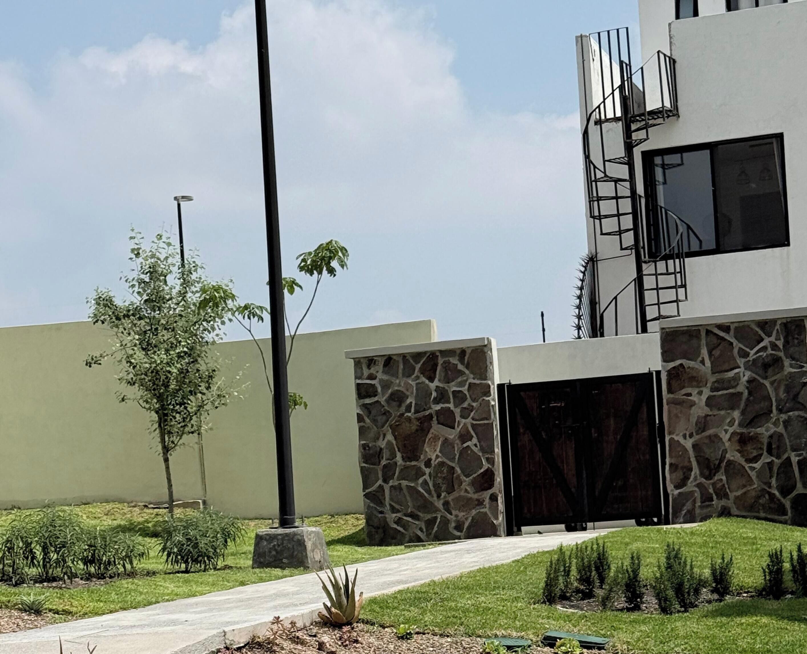 Un edificio moderno con fachada de piedra, cielo despejado y césped cuidado.