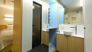 A hotel room with a bed, a door leading to a bathroom, and a mirror above the sink.