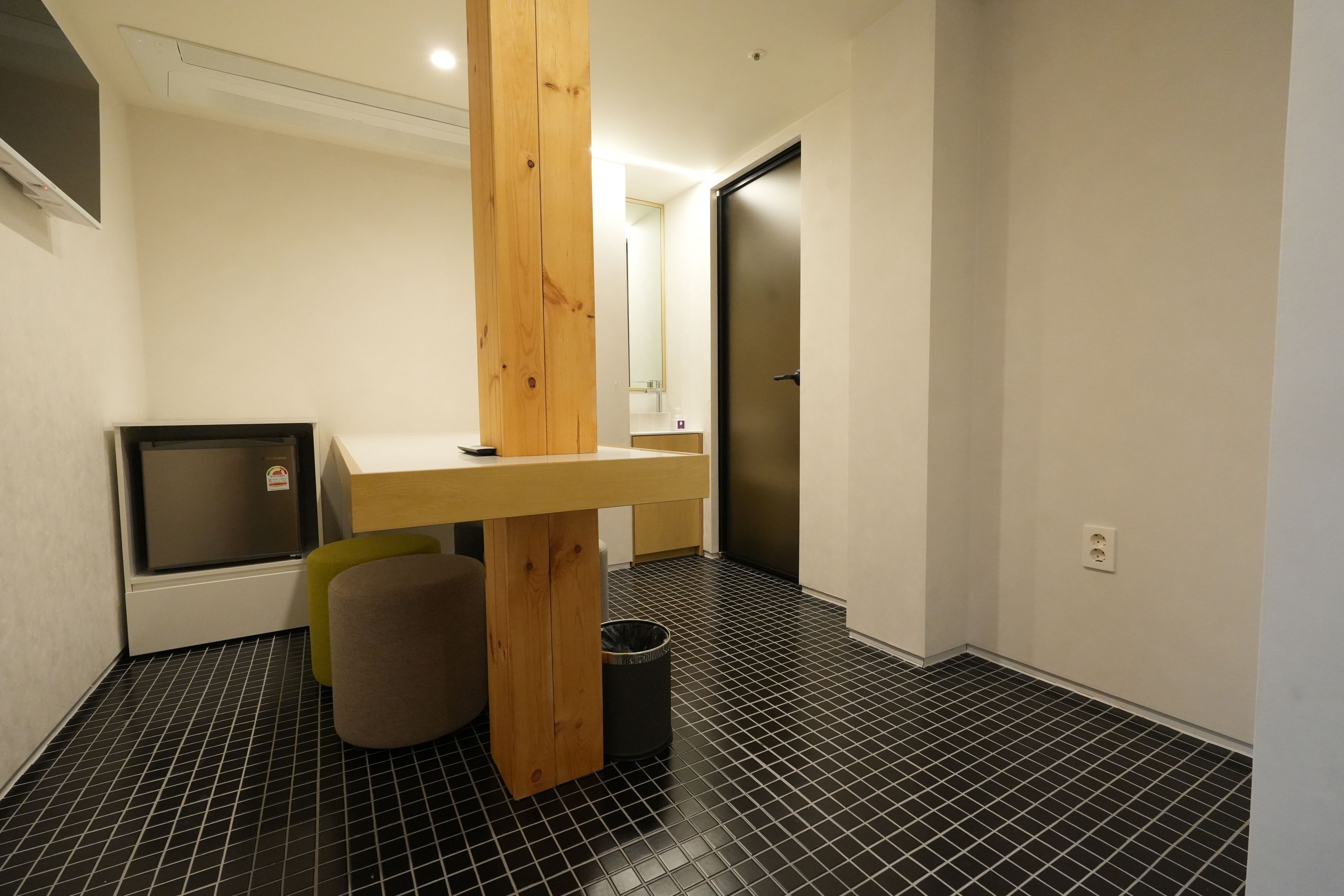 Un baño moderno con tocador de madera, un espejo y suelo de baldosas negras.