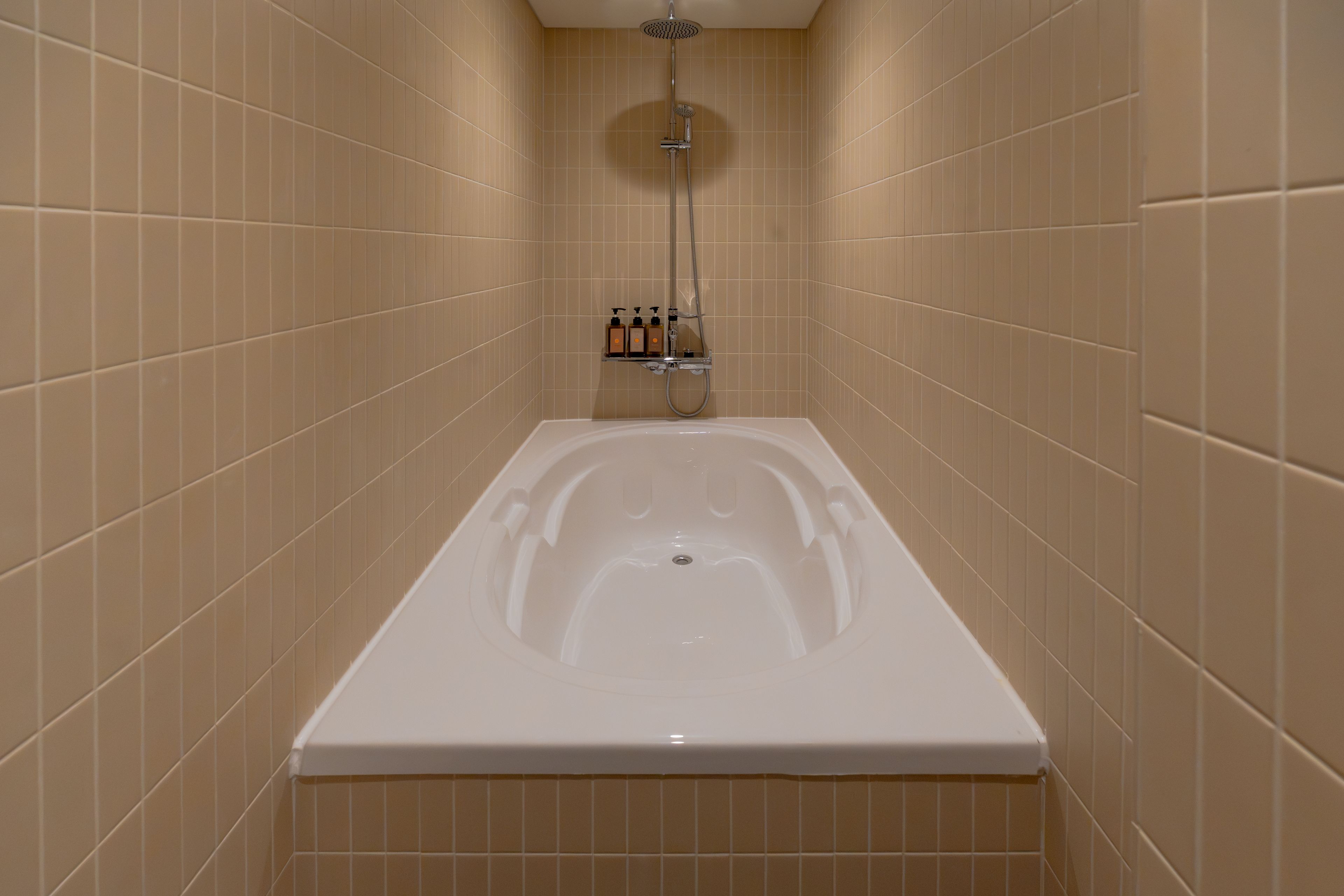 Un baño con bañera, ducha y un estante con artículos de aseo.