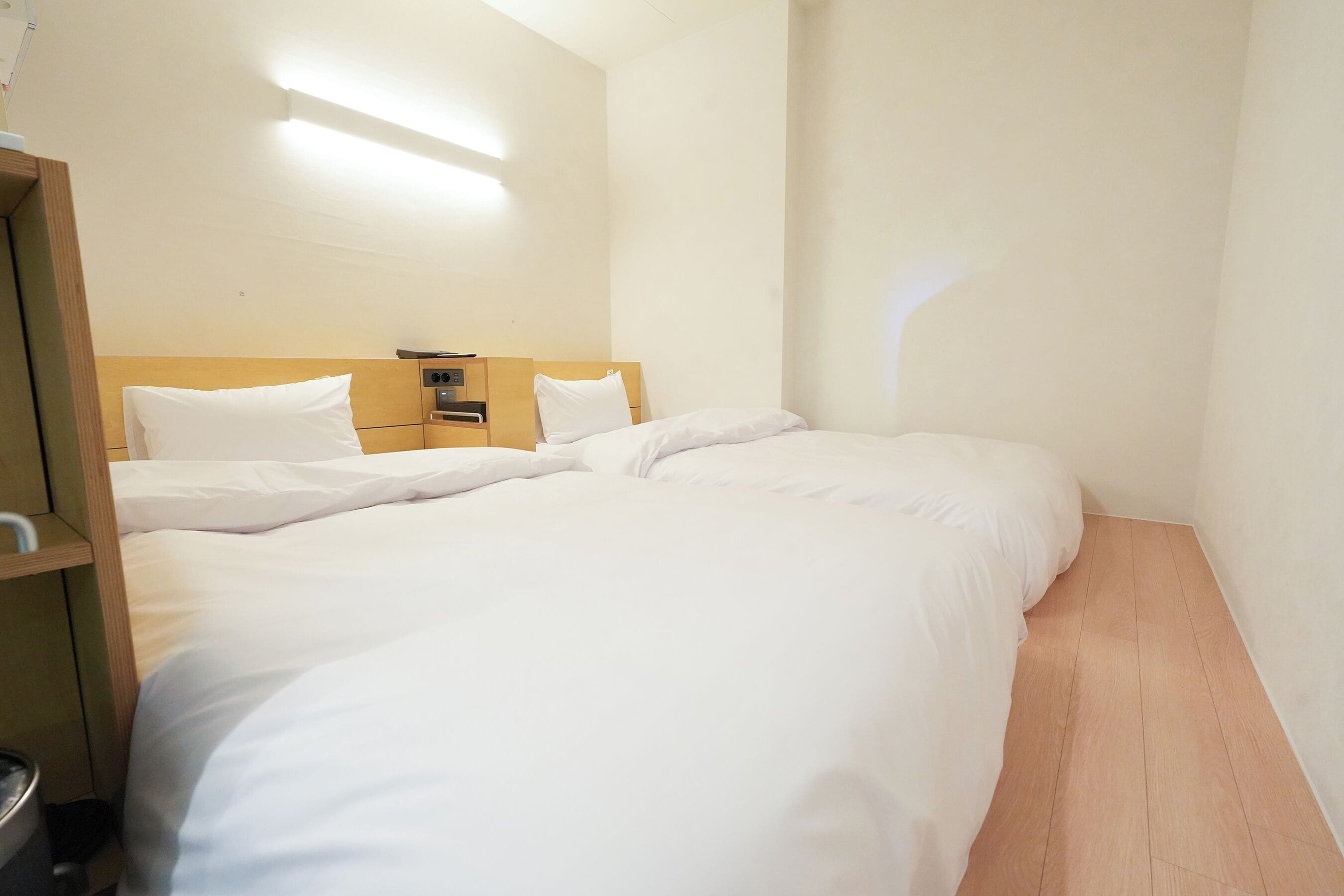 Una habitación de hotel con una cama grande, un cabecero de madera, una mesita de noche con una lámpara y una lámpara de pared.