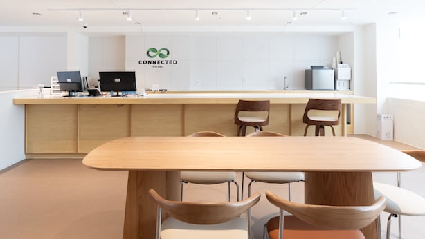 A hotel reception area with a wooden reception desk, several chairs, and a large sign reading 'CONNECTED HOTEL'.